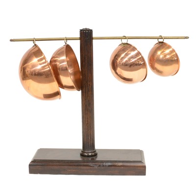 Lot 204 - Set of four copper bowls, on a wooden stand with brass rod