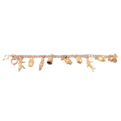 Lot 232 - A yellow metal charm bracelet with charms attached.