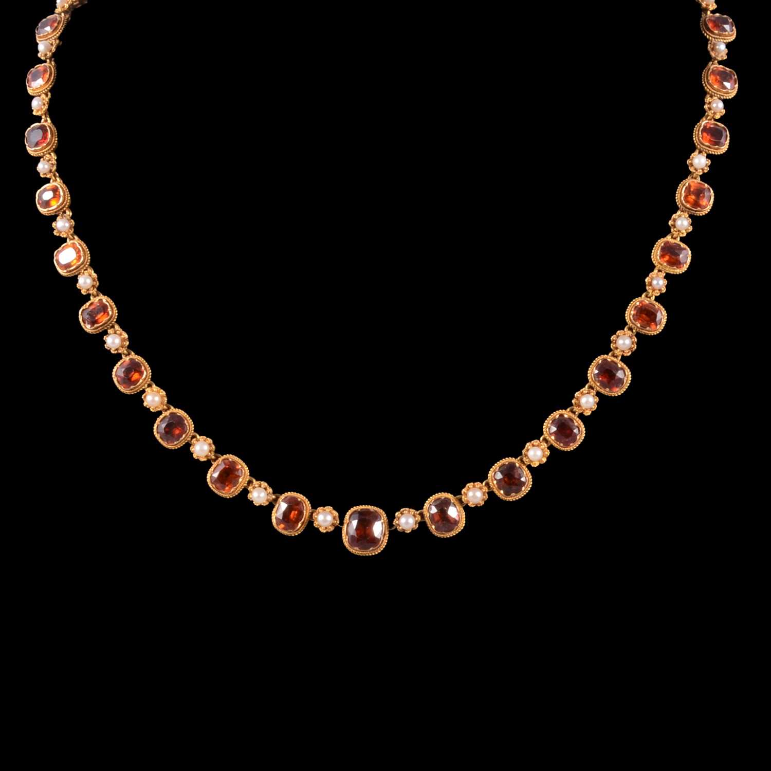 Lot 249 - A hessonite garnet and seed pearl graduated riviere necklace.