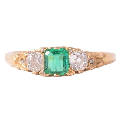 Lot 22 - An emerald and diamond three stone ring.