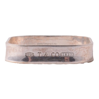 Lot 1190 - A Tiffany & Co white metal bangle, and a gilt white metal chain.