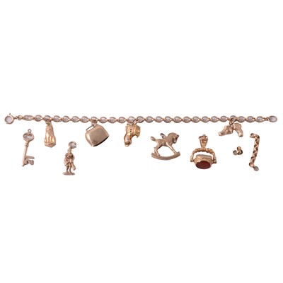 Lot 288 - A 9 carat yellow gold charm bracelet with charms attached, loose gold charms, and swivel fob.