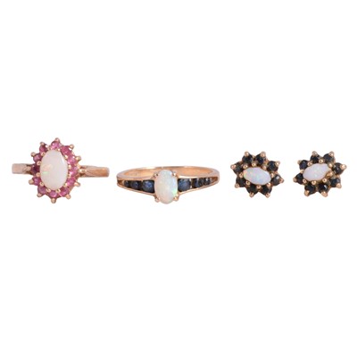 Lot 58 - An opal and ruby ring, an opal and sapphire ring, and a pair of opal and sapphire earstuds.