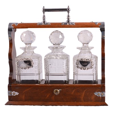 Lot 104 - An oak three-bottle tantalus with two silver wine labels, a Stuart crystal decanter.
