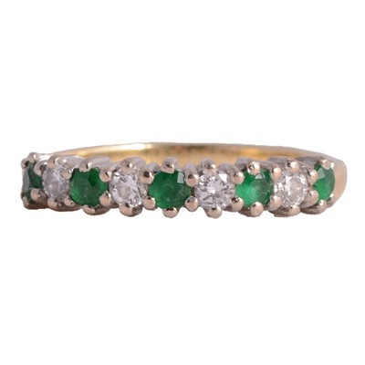 Lot 6 - An emerald and diamond half eternity ring.
