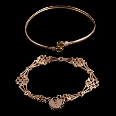 Lot 238 - A 9 carat yellow gold gate link bracelet, and a 9 carat gold peridot set sprung bangle.