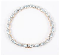 Lot 211 - A line bracelet set with twenty-three oval mixed cut aqua coloured stones