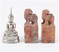 Lot 114 - Two carved red stone scroll weights and a white metal Eastern figure of Buddha (3).