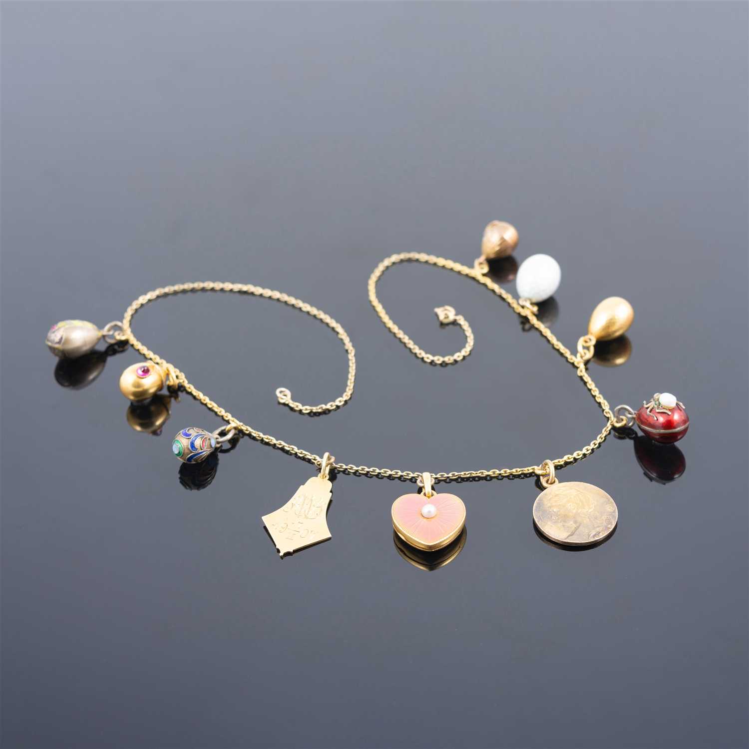 265 - A Russian yellow metal charm necklace, with two pendants and a locket by Fabergé,