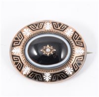 Lot 191 - A Victorian mourning brooch, an oval black agate set to centre with a decorative border of black and white enamel, vacant locket back, overall dimensions 40mm x 35mm.