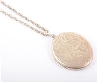 Lot 247 - A silver oval locket with scroll engraved decoration to front, 45mm x 35mm on a Prince-of-Wales link chain 65cm long.