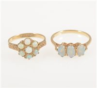 Lot 225 - A 9 carat yellow gold ring set with three oval cabochon opals, ring size M and a 9 carat yellow gold circular cluster ring set with seven round cabochon cut opals, ring size L. (2)