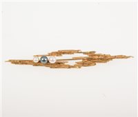Lot 266 - A 1960s 9 carat yellow gold bark textured brooch 7cm long, set with two white and one black pearl