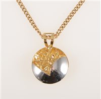 Lot 253 - An 18 carat yellow and white gold 20mm circular pendant, half polished and half with open wire work approximate weight 3.5gms on a 9 carat yellow gold flat curb link chain 60cm long, 10gms.