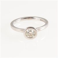 Lot 258 - A diamond solitaire ring, the brilliant cut stone in a halo rubbed over 18 carat white gold setting, 2mm wide D shape shank and shoulders