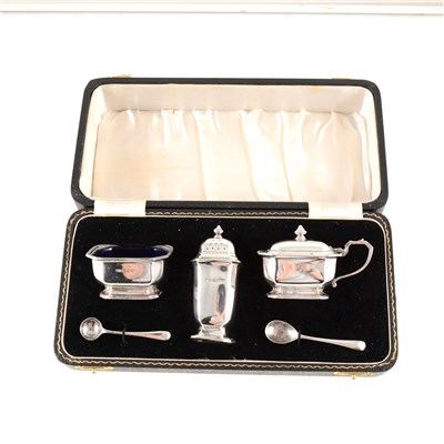 Lot 179 - A silver condiment set by William Suckling Ltd, Birmingham 1946, comprising salt with blue glass liner, pepperette and mustard, with two spoons, cased, weight approx. 3.7oz.