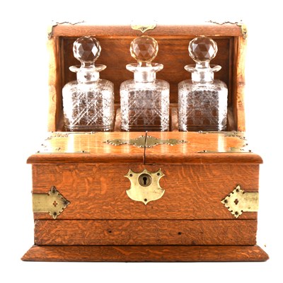 Lot 189 - An Edwardian oak Tantalus, metal applique, ...