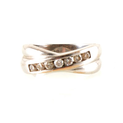 Lot 143 - An 18 carat white gold crossover ring channel set with seven brilliant cut diamonds.