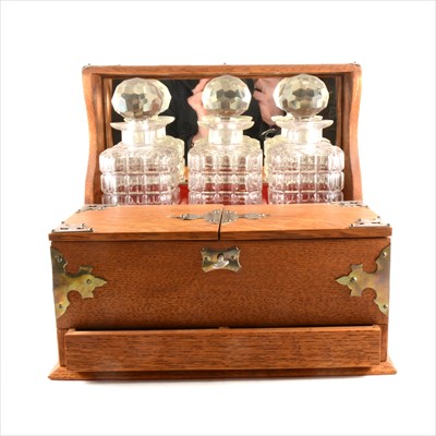 Lot 166 - An Edwardian oak Tantalus, with two hinged compartments and a drawer under
