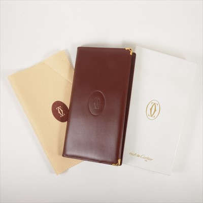 Lot 705 - Must de Cartier - a burgundy leather wallet with multiple leaves to hold business cards.