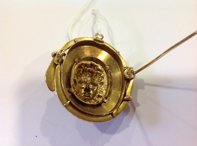 Lot 69 - A late 19th Century yellow metal and enamel oval brooch, with a central mask in high relief.