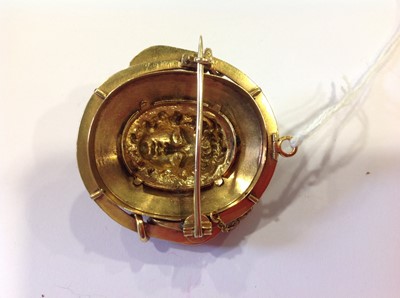 Lot 69 - A late 19th Century yellow metal and enamel oval brooch, with a central mask in high relief.