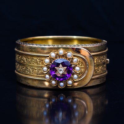 Lot 94 - A late 19th Century yellow metal bangle with an amethyst, diamond and pearl cluster.