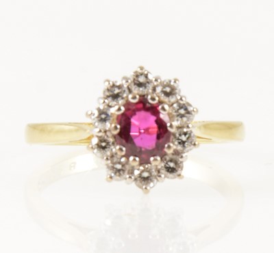 Lot 26 - A ruby and diamond oval cluster ring.