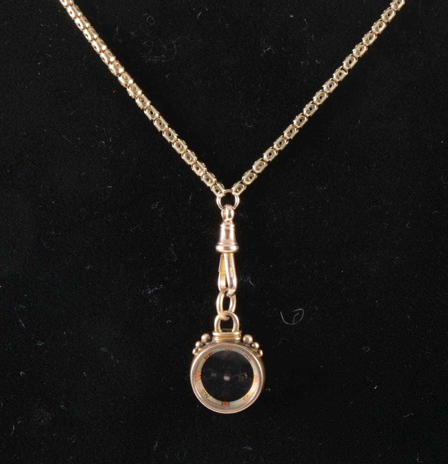 Lot 106 - A yellow metal short guard chain and compass fob.
