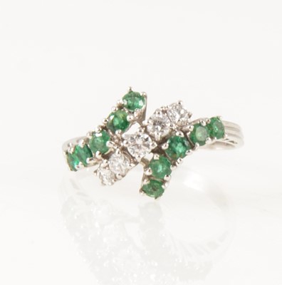 Lot 1268 - An emerald and diamond crossover ring.