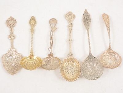 Lot 1201 - Six ornate silver and white metal sugar sifting spoons.
