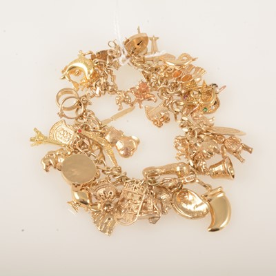 Lot 356 - A 9 carat yellow gold curb link bracelet with forty-three charms.