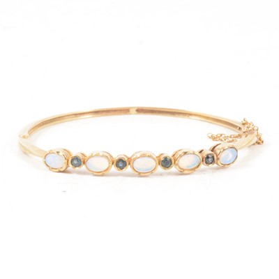 Lot 349 - A 9 carat yellow gold bangle set with opals and sapphires.
