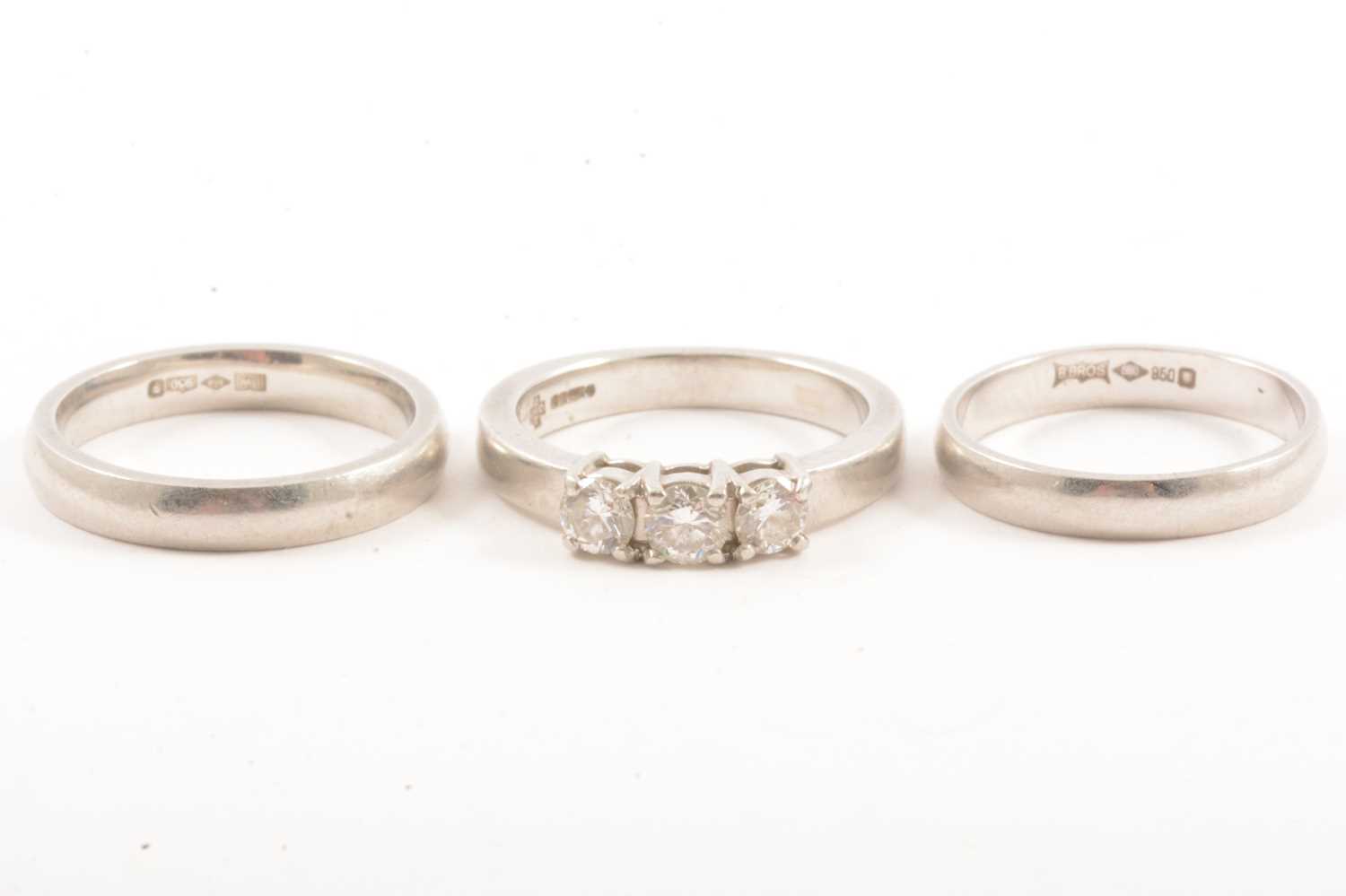 Lot 9 - A diamond three stone ring and two platinum wedding bands.