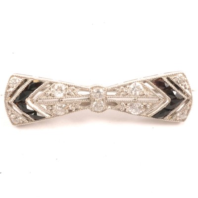 Lot 253 - Tiffany & Co - a diamond and black onyx bow brooch.